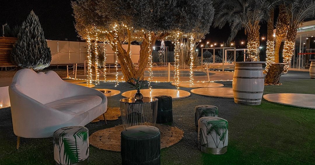 Jardín de la finca decorado por microbombilla con cómodos sillones y taburetes de diseño elegante.