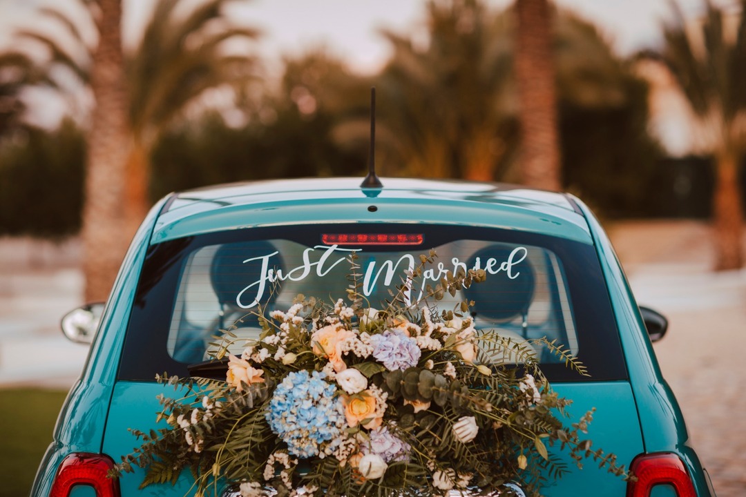 Coche de bodas azul celeste con ramo de flores.